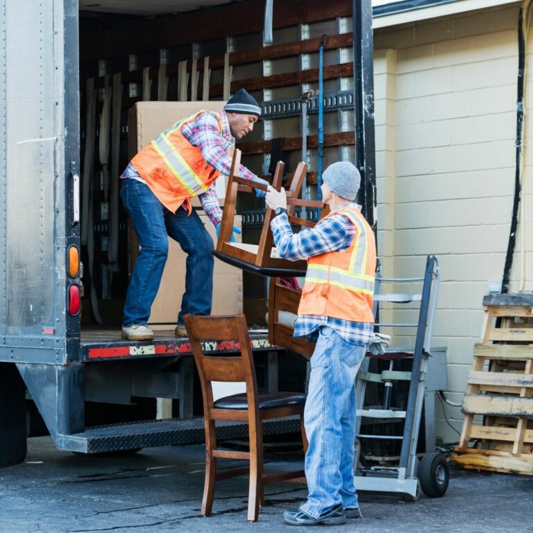Two employees loading furniture into a Dump The Junk truck.