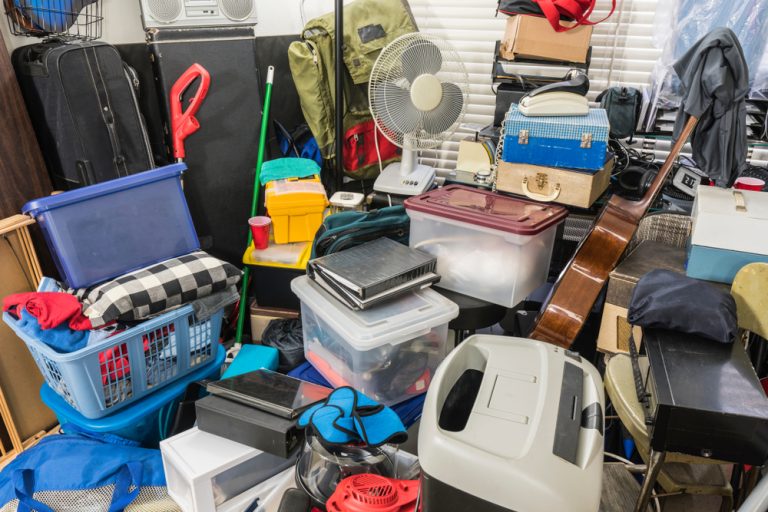 Cluttered storage filled with boxes, decades-old electronics, files, and household items.
